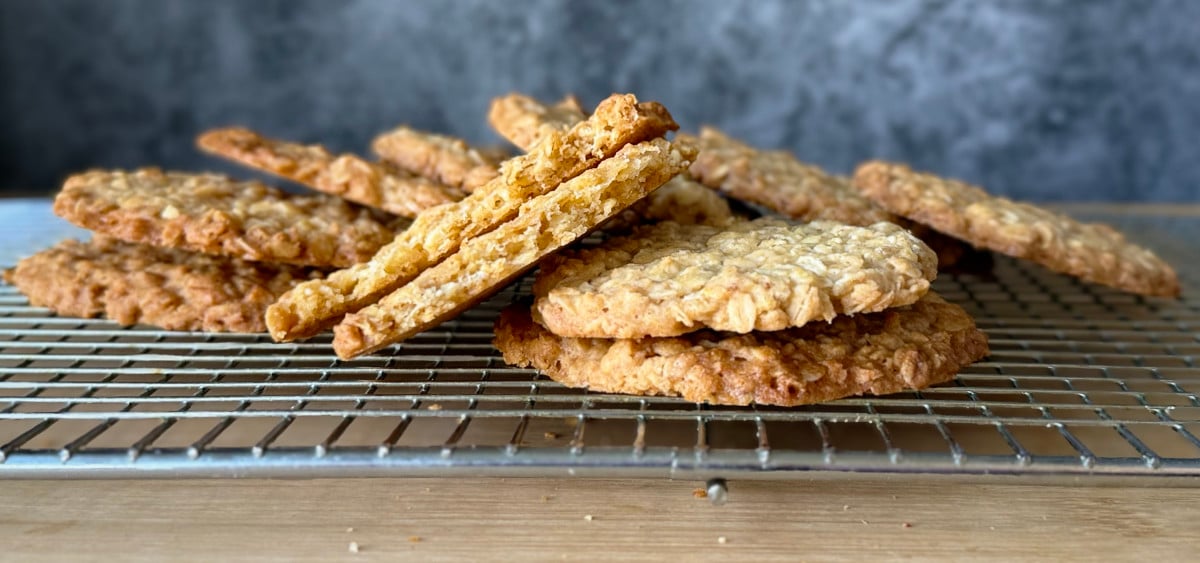 Cooling biscuits on a rack with one snapped in half to show how crispy it is.