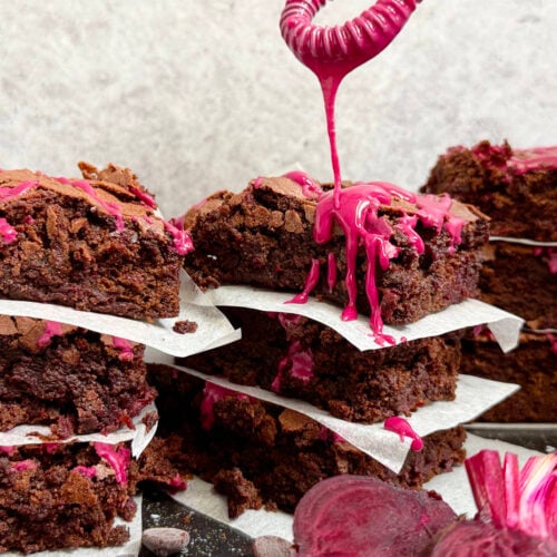 A whisk dripping icing over stacks of cake.