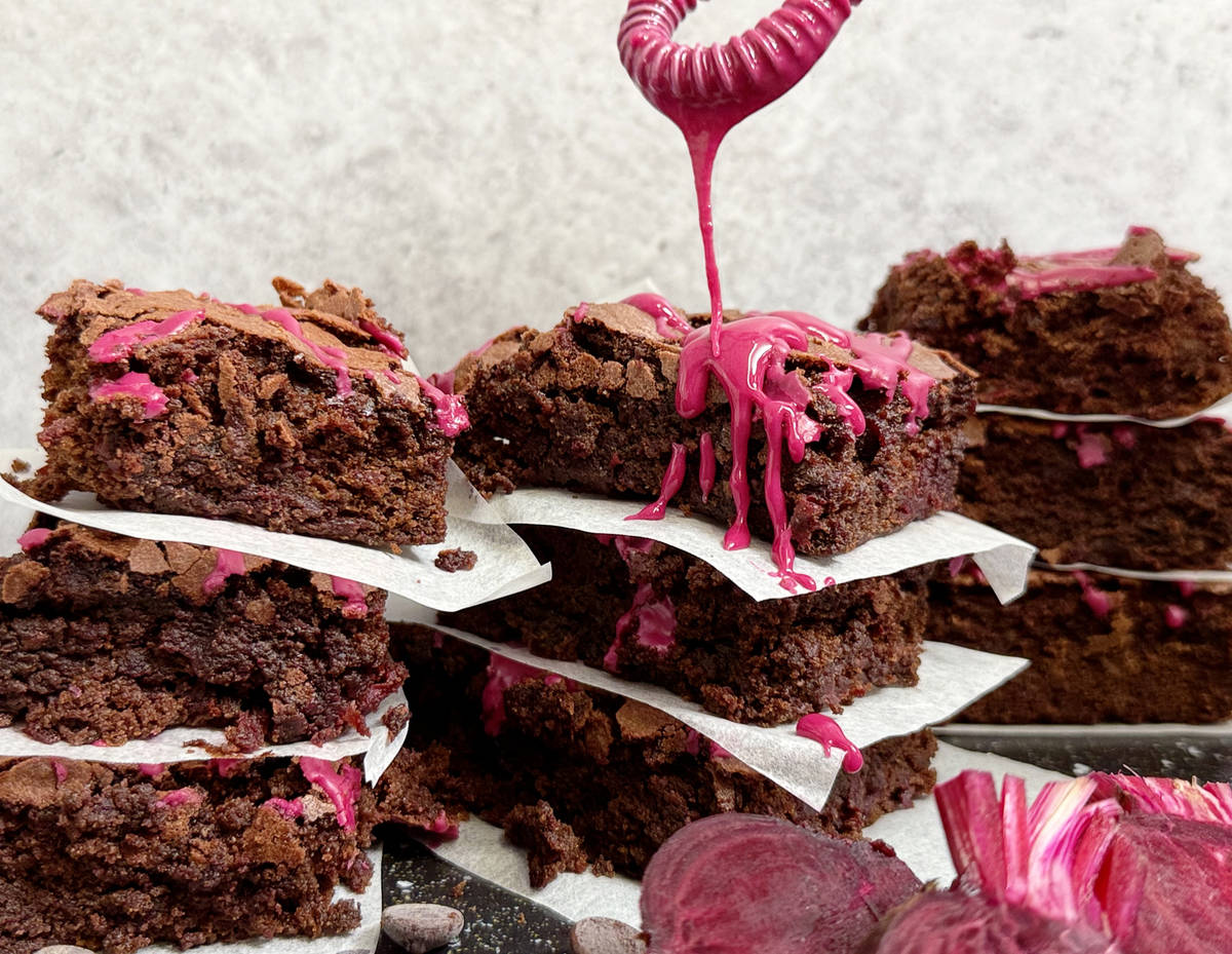 A whisk dripping icing over stacks of cake.